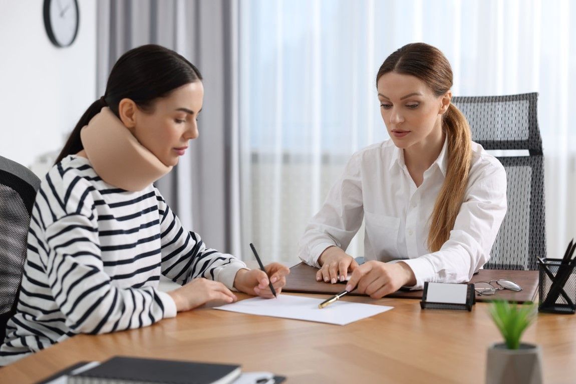 An image of an attorney and an injured client signing documents.