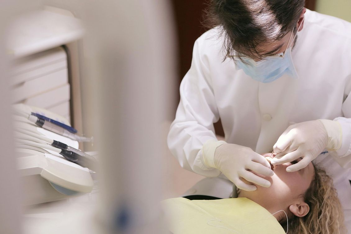 A dentist is examining a patient 's teeth in a dental office.