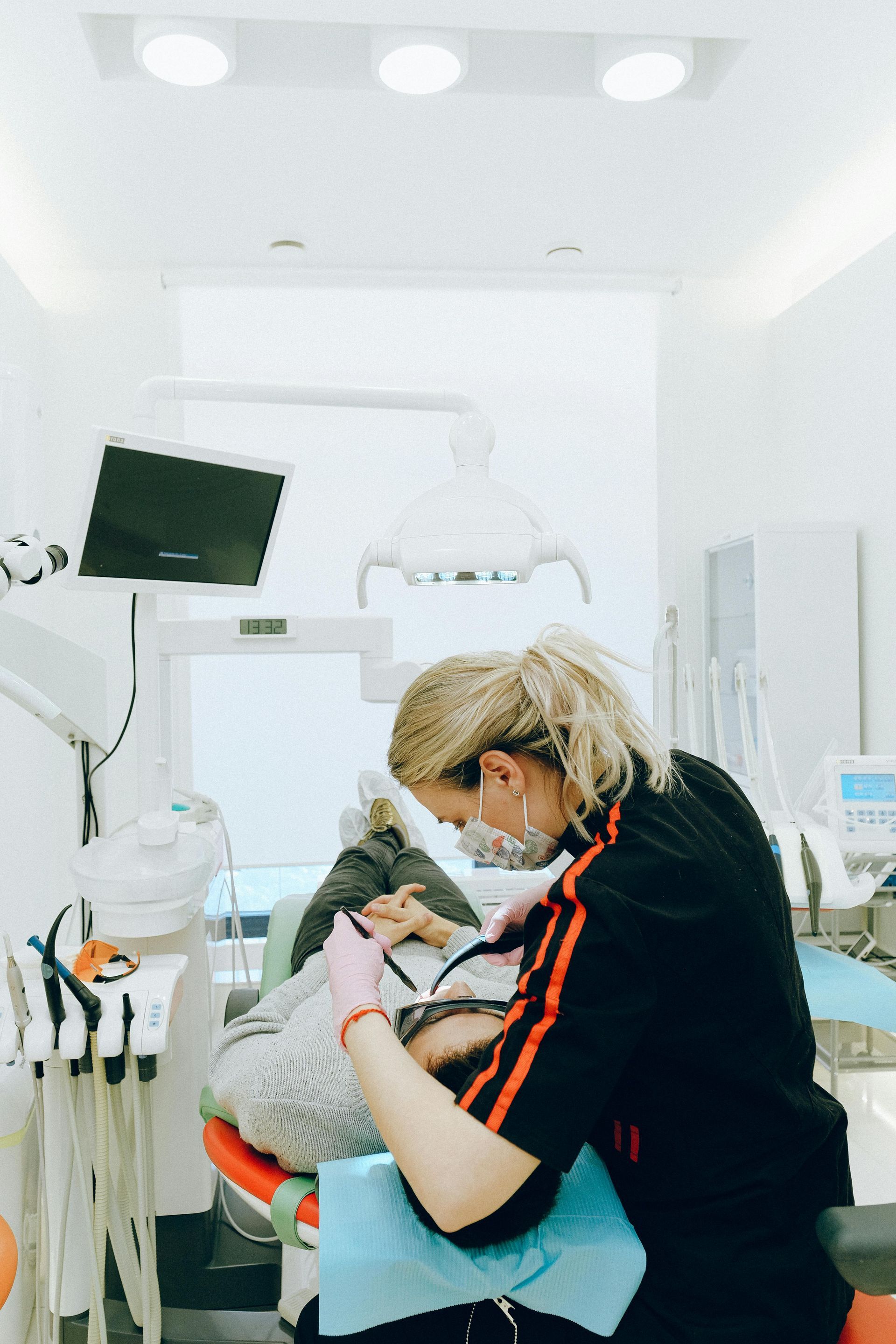 A woman is working on a child 's teeth in a dental office.