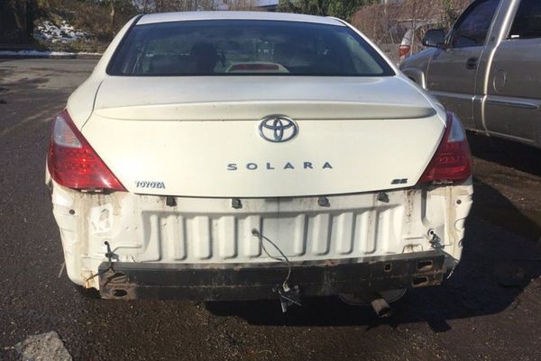 A white car is wrecked in a parking lot