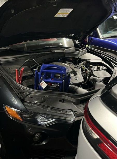 A black car is getting a jump start in a garage