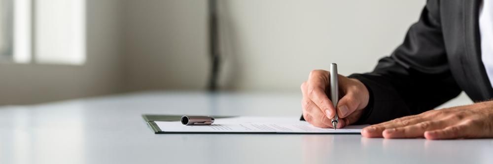 A Person Is Sitting At A Table Writing On A Clipboard With A Pen — Cairns Caravan Repairs In Edmonton, QLD