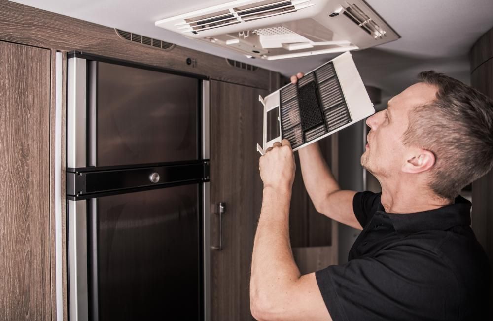 A Man Is Fixing A Ceiling Fan In A Camper Van — Cairns Caravan Repairs In Edmonton, QLD
