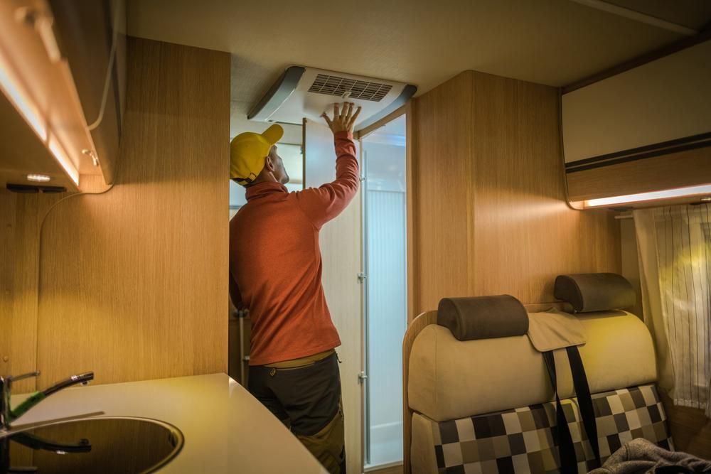 A Man Is Adjusting The Aircon In A Camper Van — Cairns Caravan Repairs In Edmonton, QLD