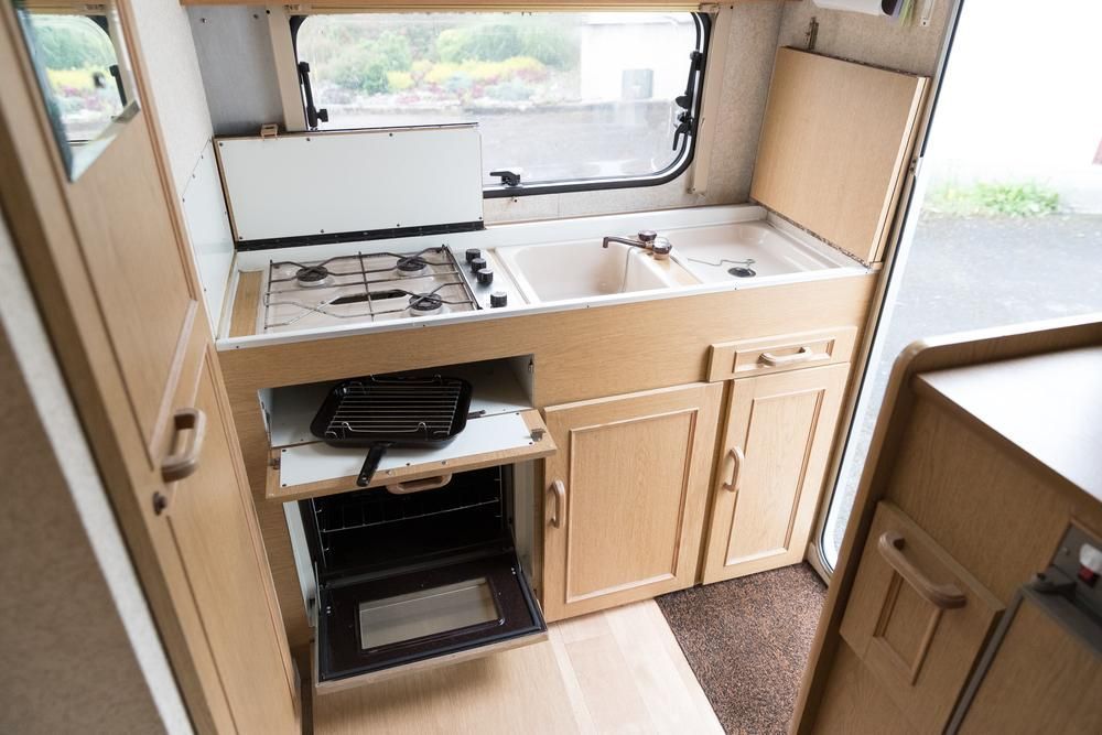 A Kitchen In A Camper With A Stove, Sink, And Oven — Cairns Caravan Repairs In Edmonton, QLD