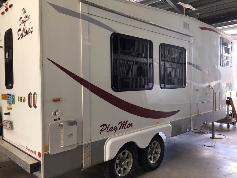 A White Rv With A Red Stripe On The Side Is Parked In A Garage — Cairns Caravan Repairs In Edmonton, QLD