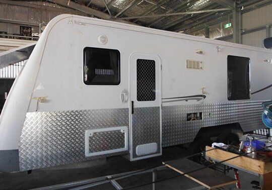 A White And Silver Camper Is Parked In A Garage — Cairns Caravan Repairs In Edmonton, QLD
