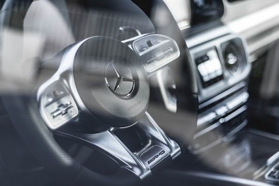 Mercedes-Benz AMG steering wheel with paddle shifters, seen through the windshield.