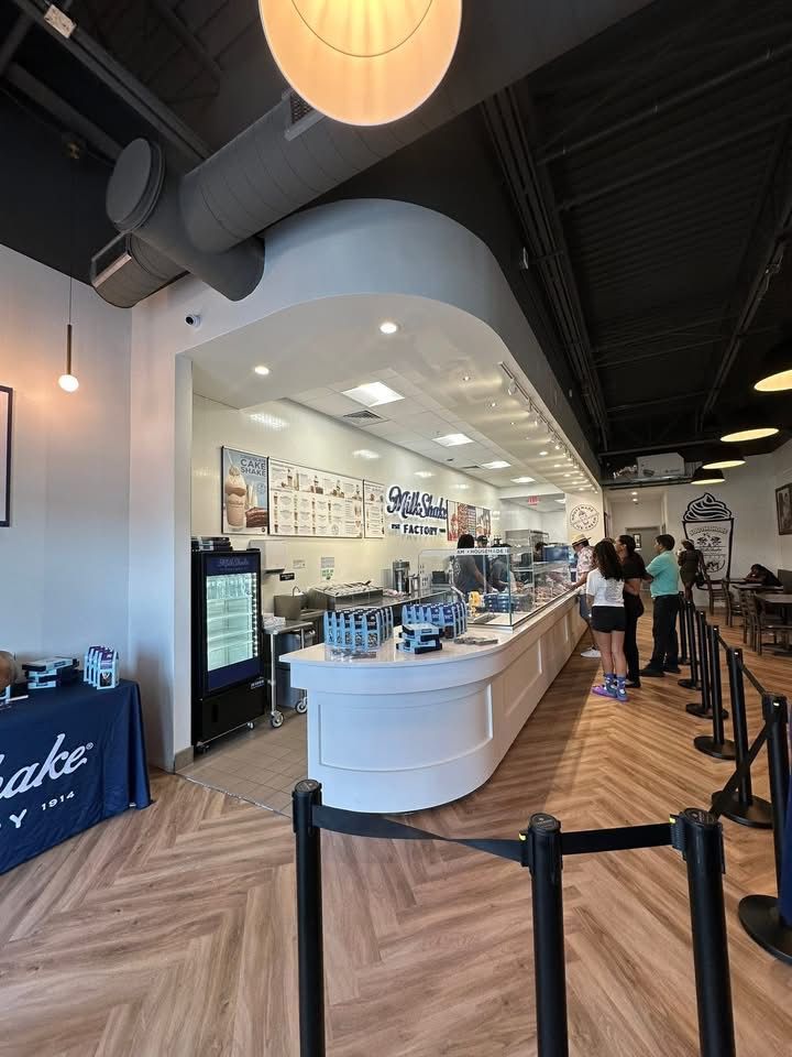 Interior of an ice cream shop with a counter, customers, and a display of menu items.