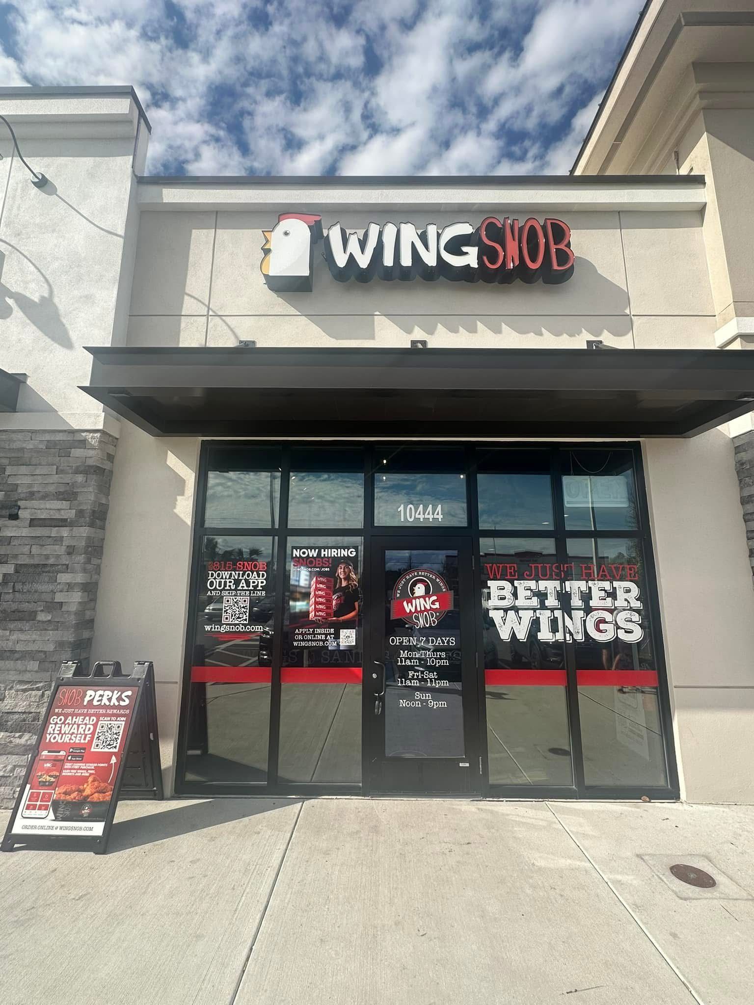 Exterior of Wingstop restaurant with sign and awning. Door displays