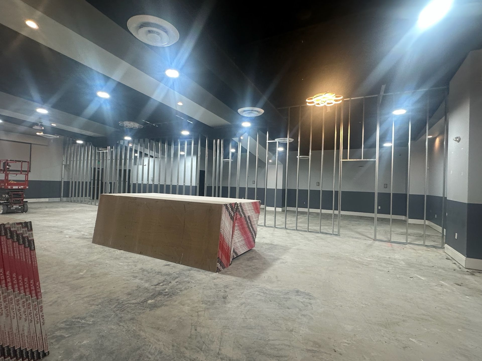 Interior construction of a commercial space with exposed metal framing, drywall, and overhead lighting.