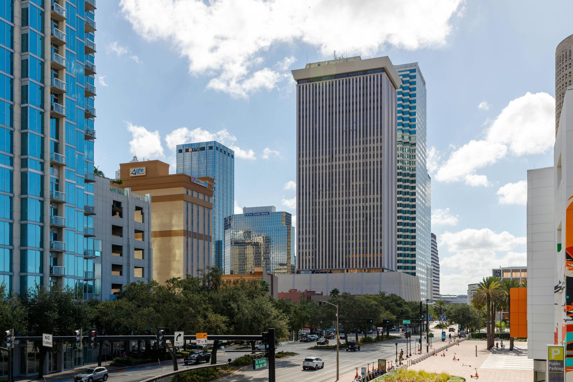 Downtown Tampa cityscape with tall buildings, a street, blue sky, and clouds.
