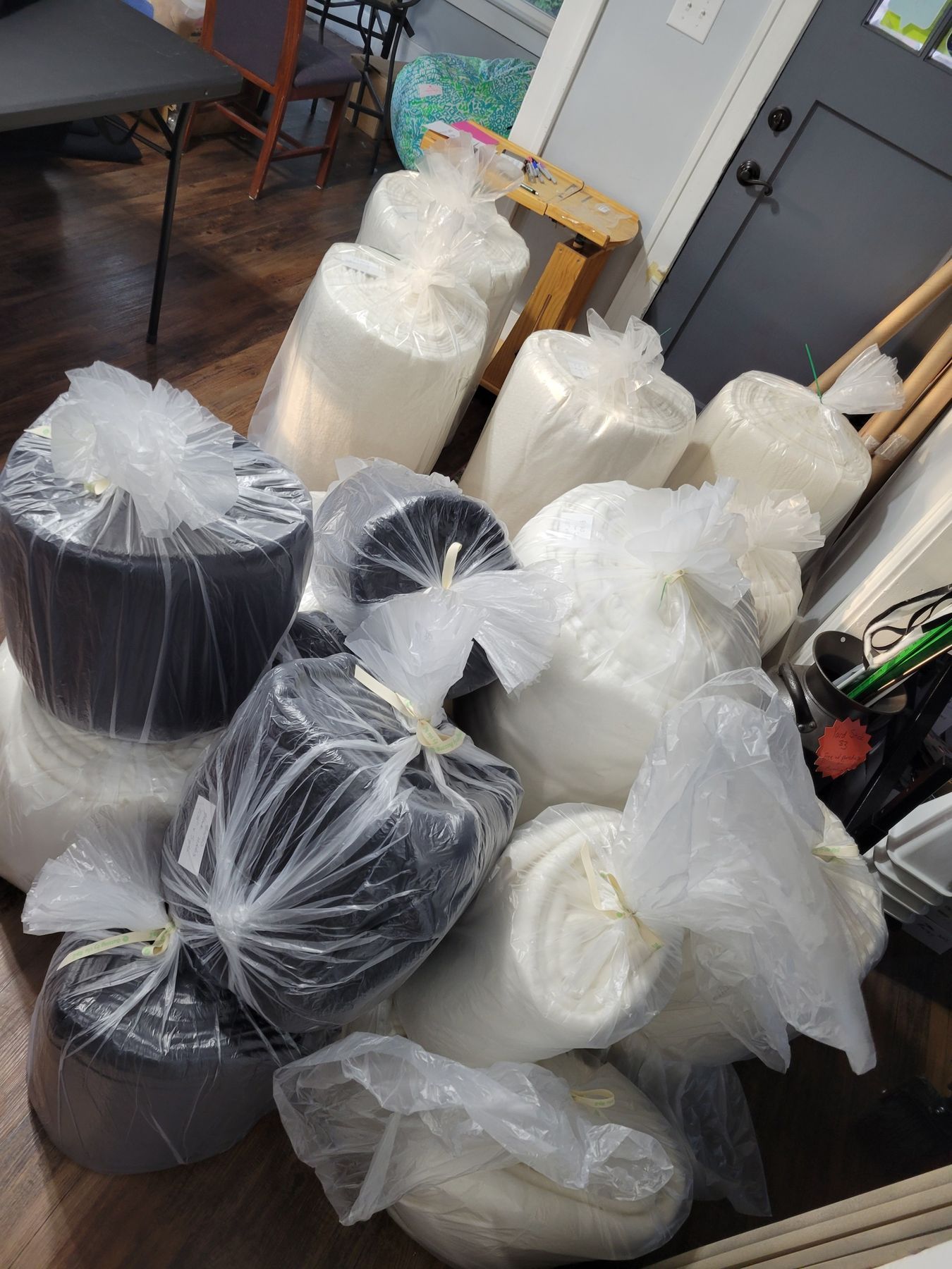 Several rolls of fabric wrapped in plastic, stacked on a table in a workshop.