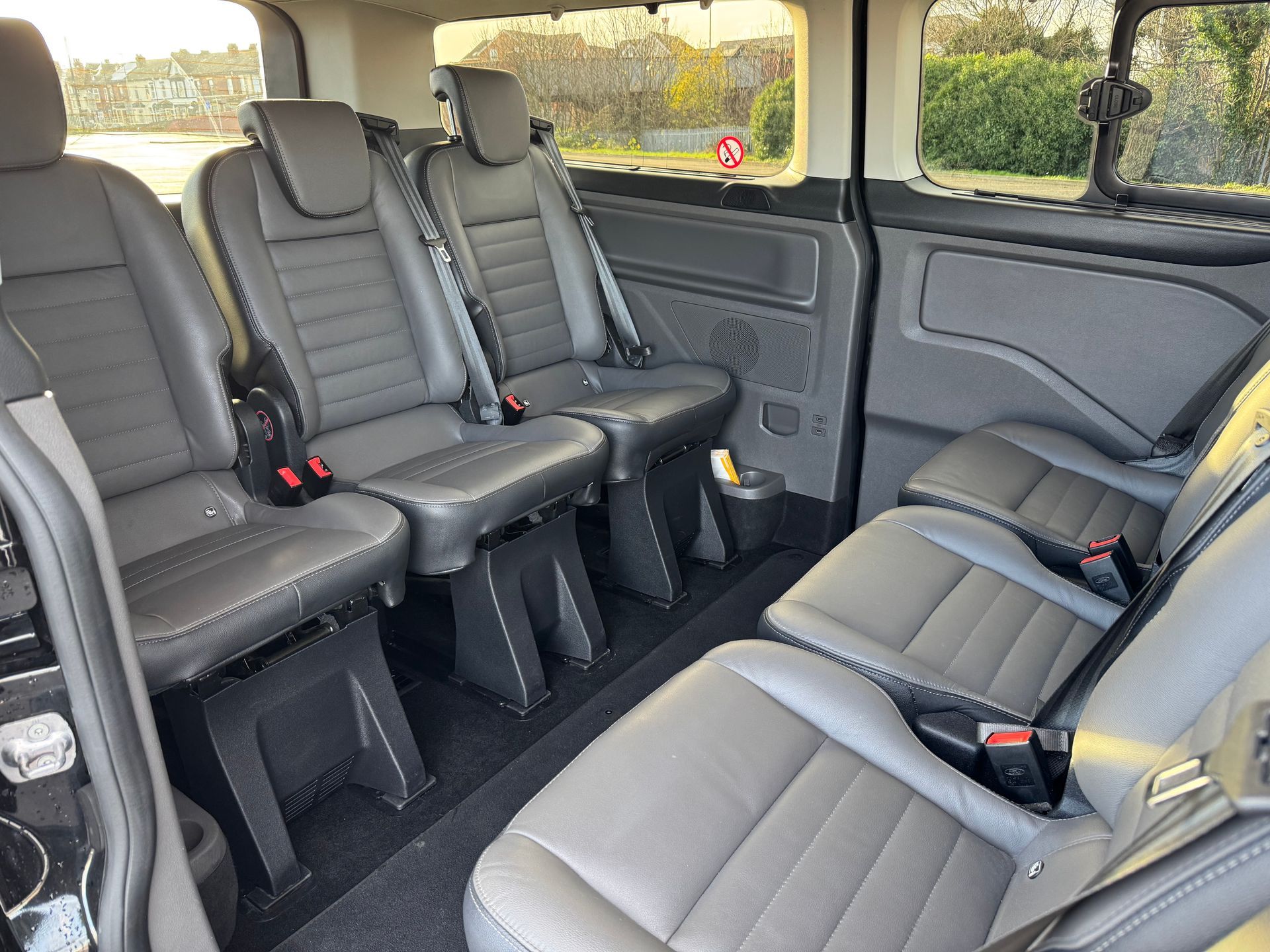 Interior view of a black van with six gray leather seats.
