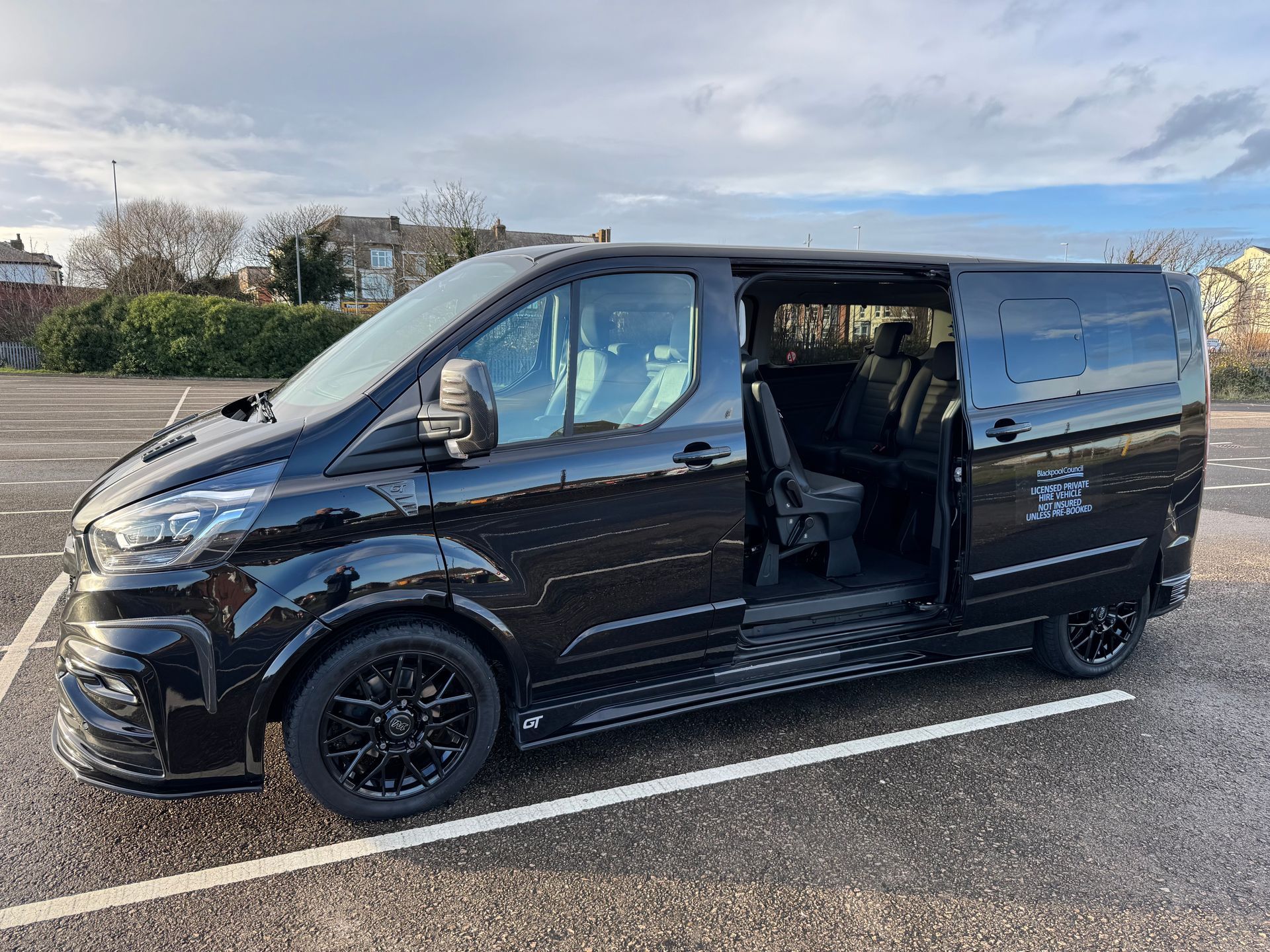 Black custom van with open sliding door parked on asphalt.