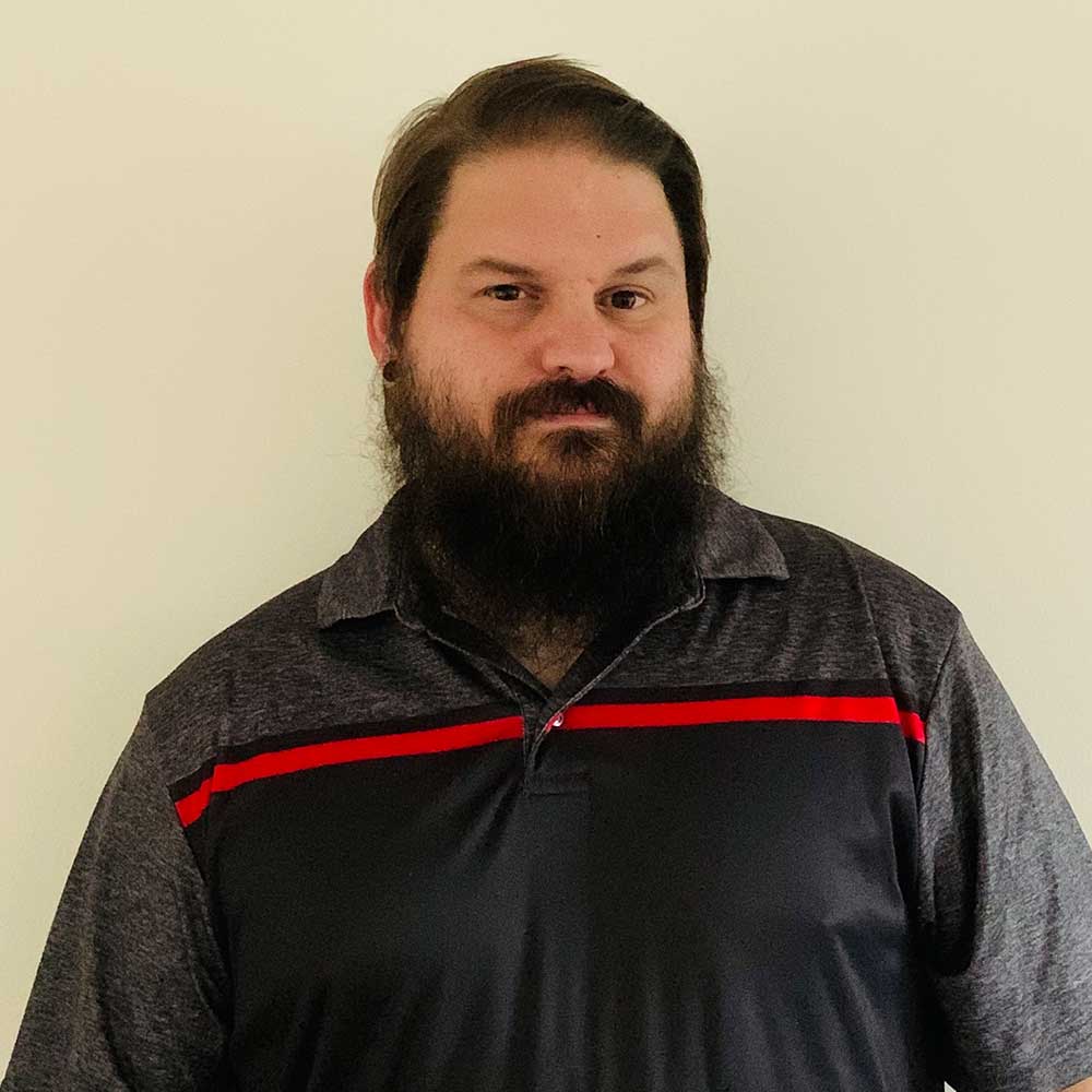 A man with a beard is wearing a black and red shirt.
