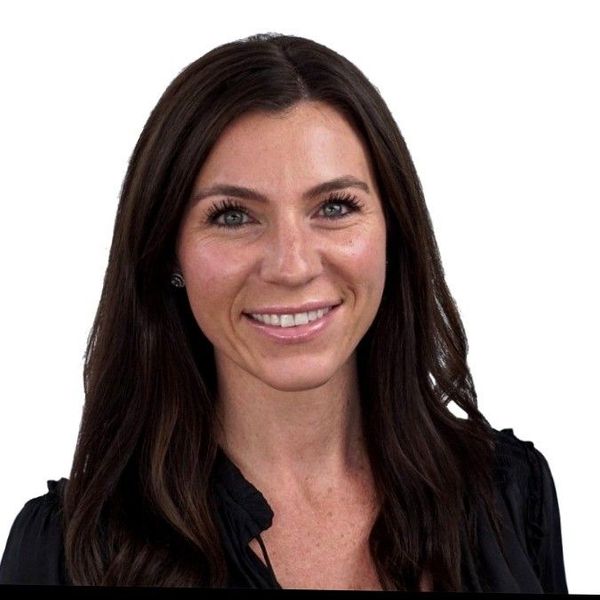 A man is holding a dog in his arms and the dog is wearing a sweater.