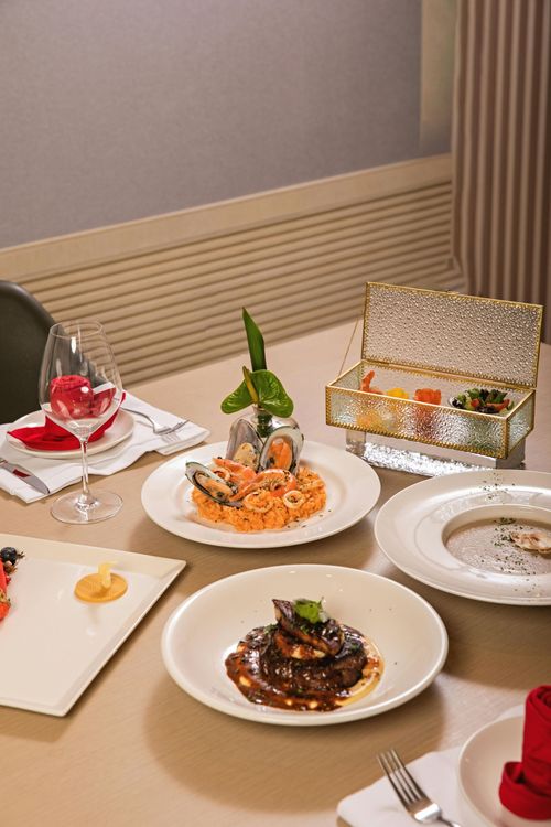 Elegant restaurant table with plated dishes, dessert, and a sparkling gift box centerpiece