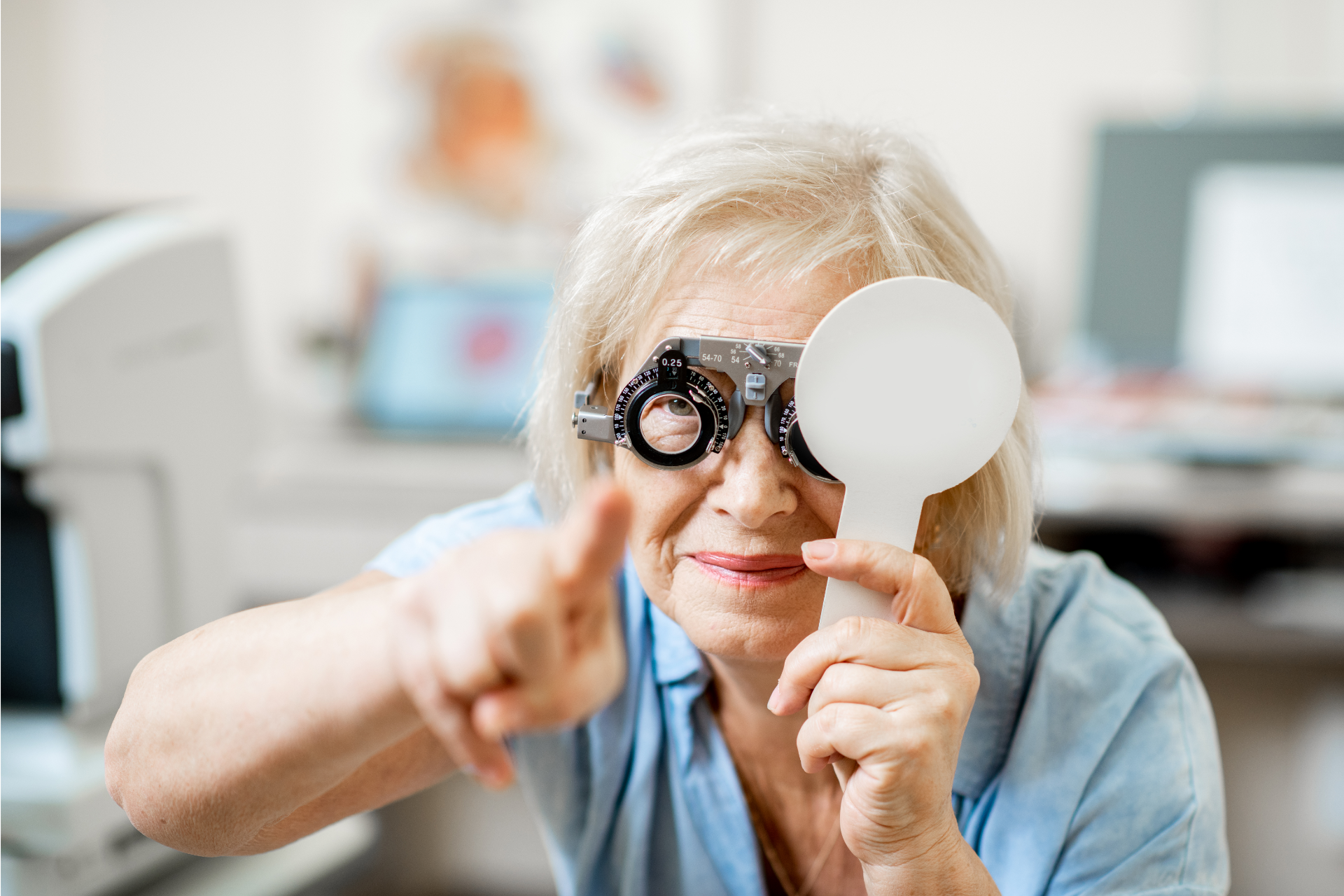 Woman at eye doctor, holding a lens testing device and pointing.