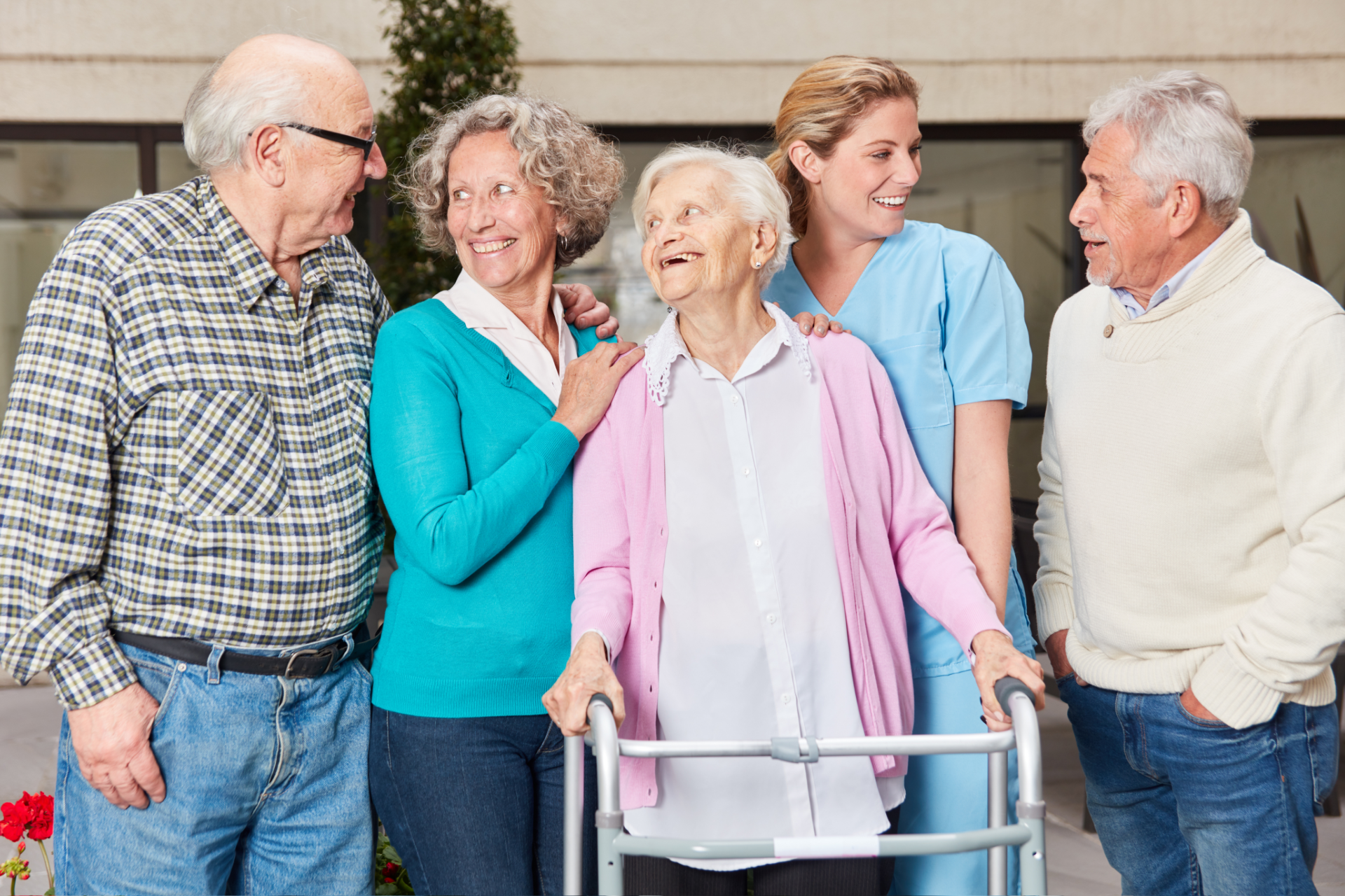 Group of seniors and a caregiver smiling together outdoors.