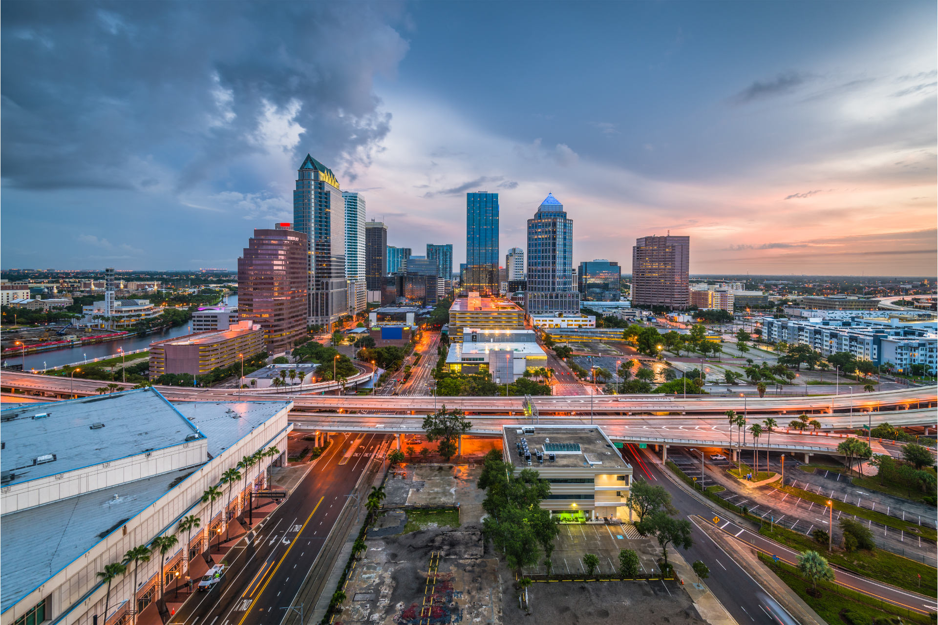 Skyline of Tampa, Florida at dusk with buildings, roads, and cloudy sky.