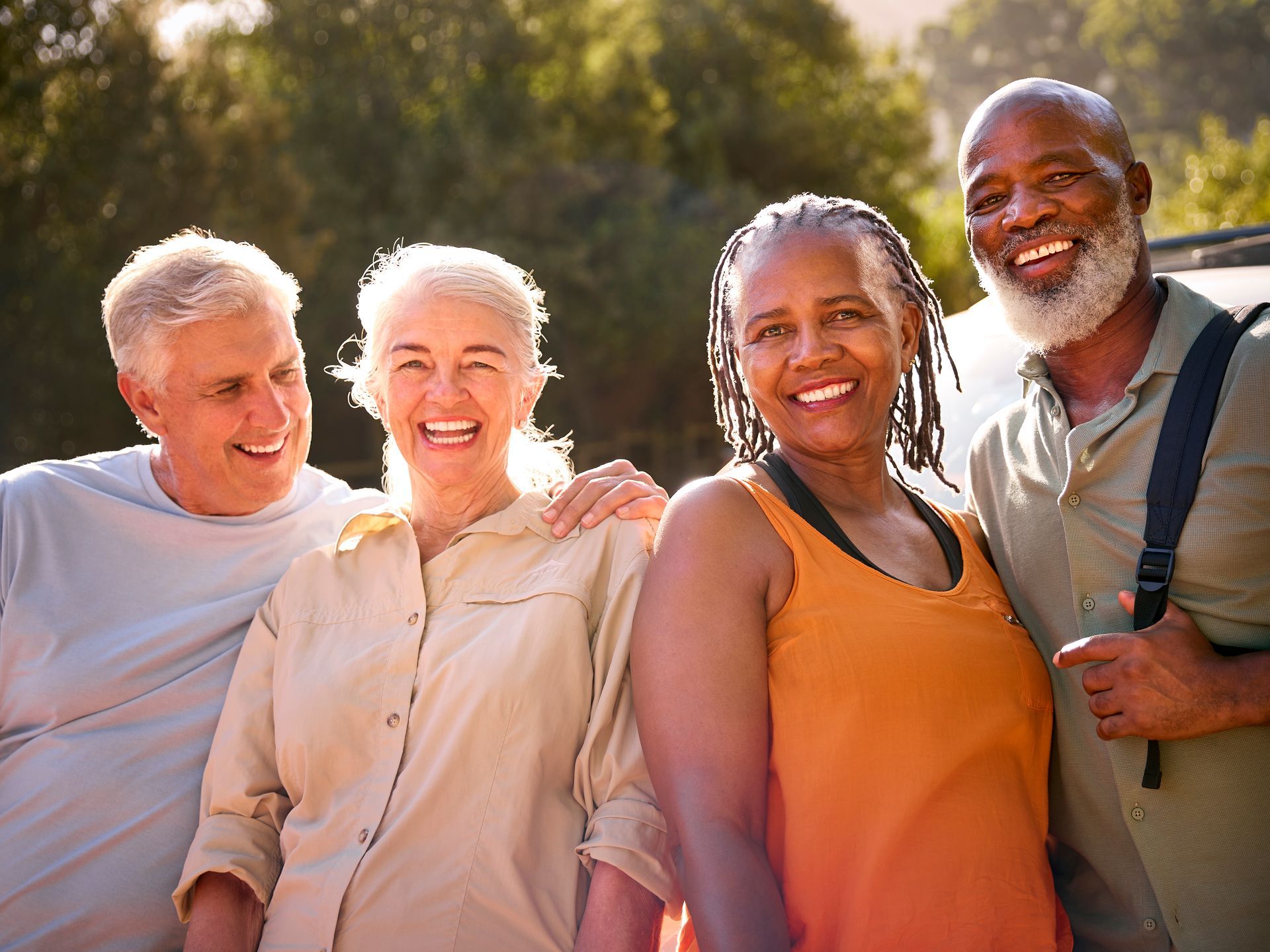 Four smiling senior friends in outdoor setting; two men, two women.