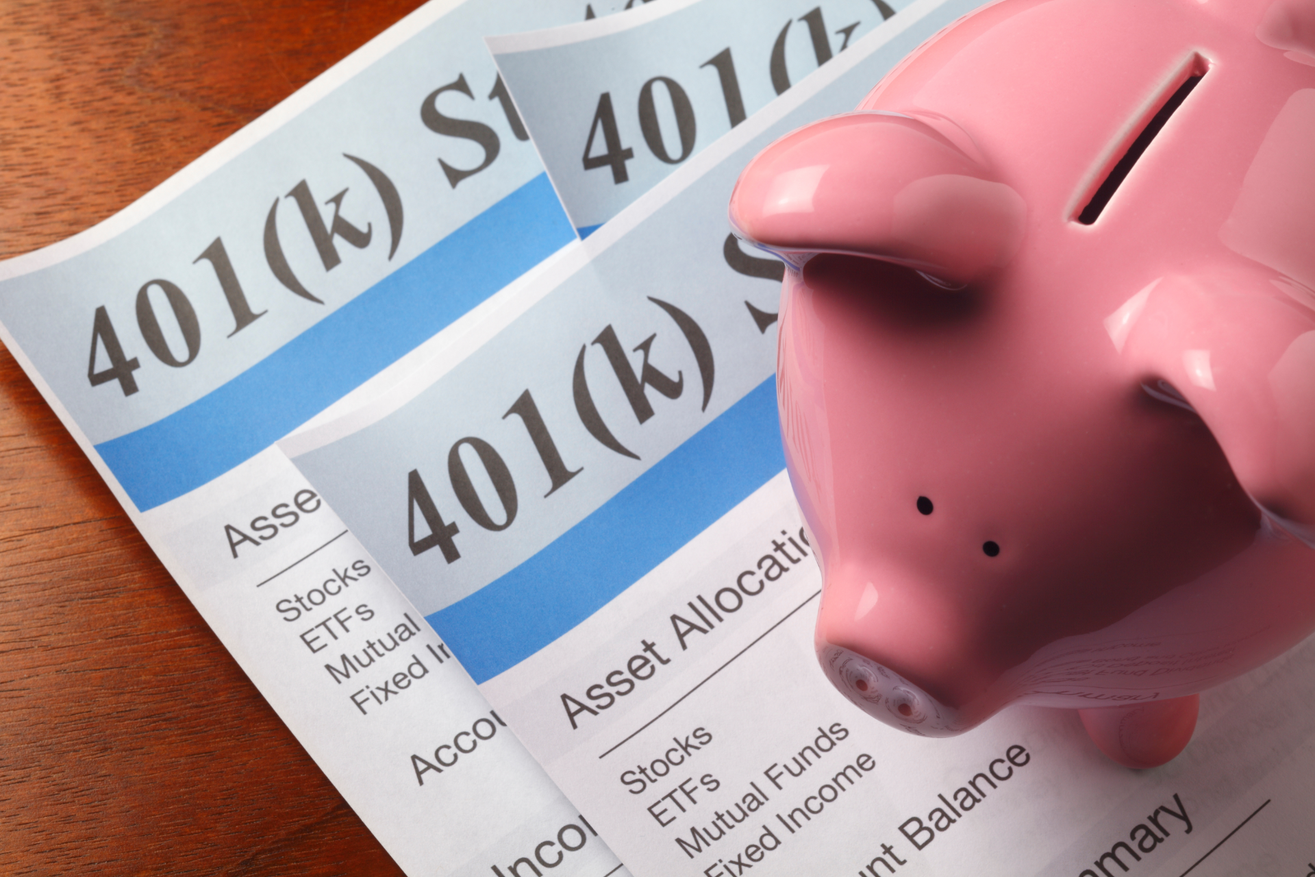 Pink piggy bank next to three 401(k) asset allocation documents with investment details.
