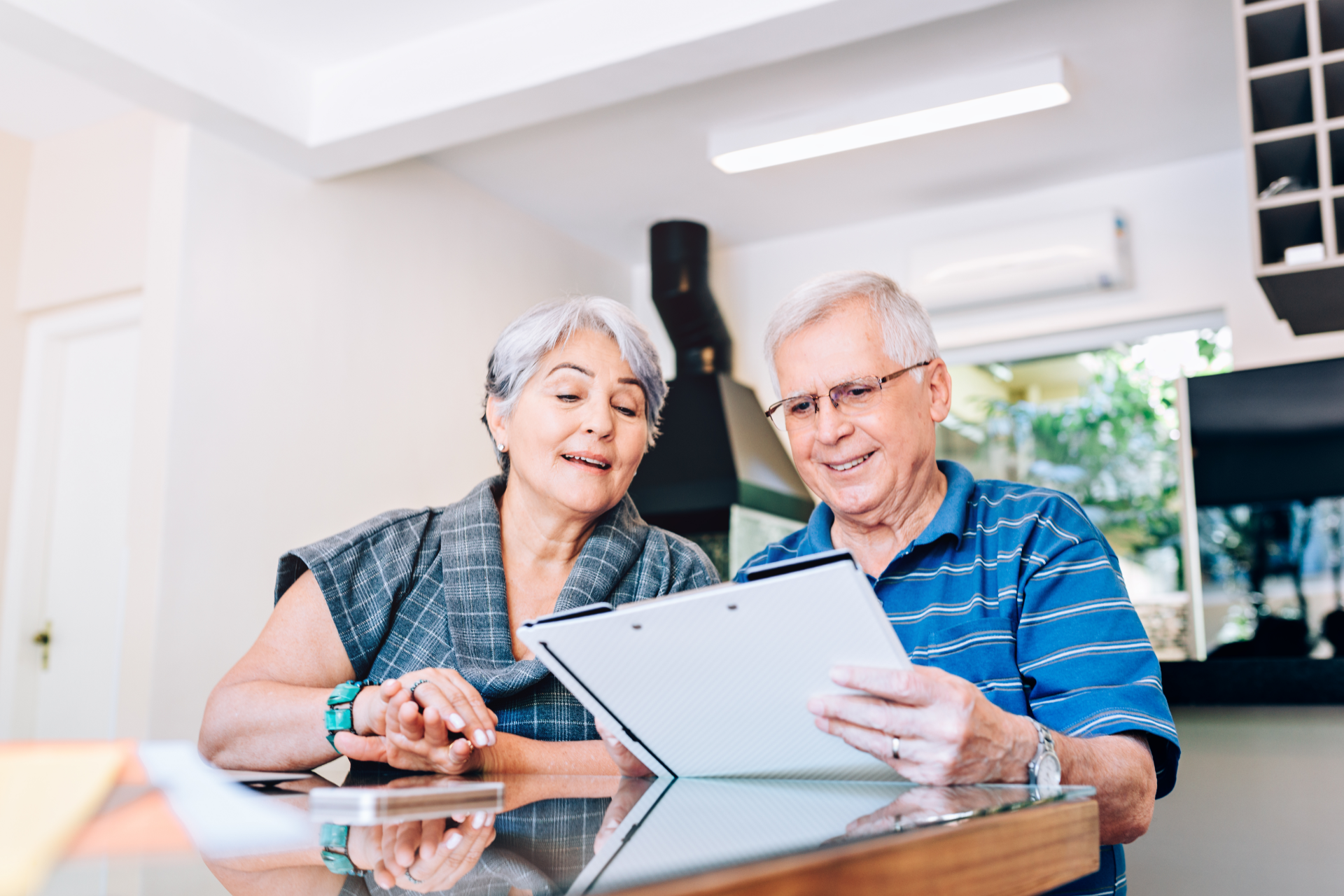 Elderly couple looking at a clipboard together, smiling indoors.
