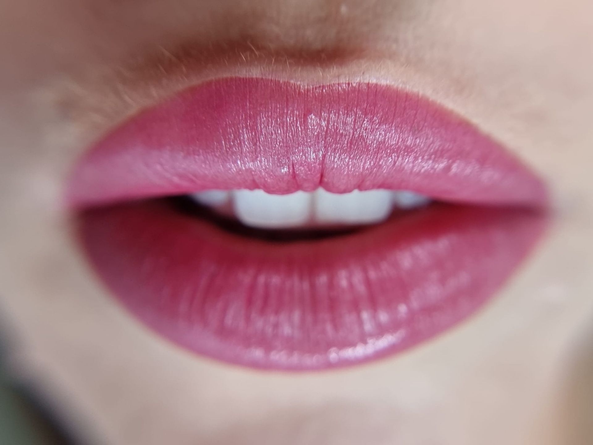 Eine Nahaufnahme der Lippen einer Frau mit rosa Lippenstift und weißen Zähnen.