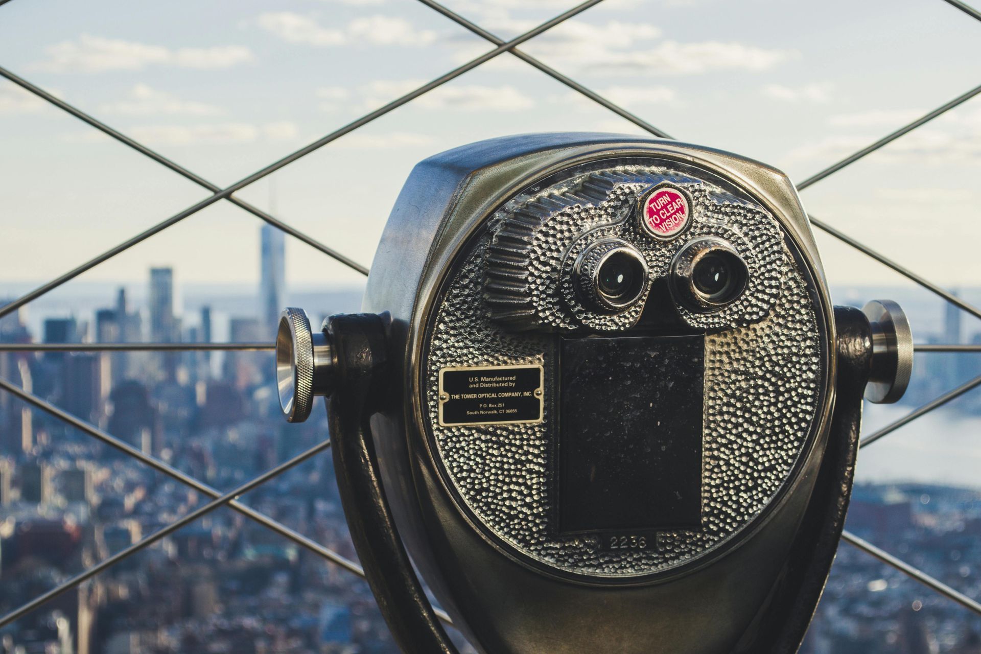 A coin operated binoculars is looking out over a city.