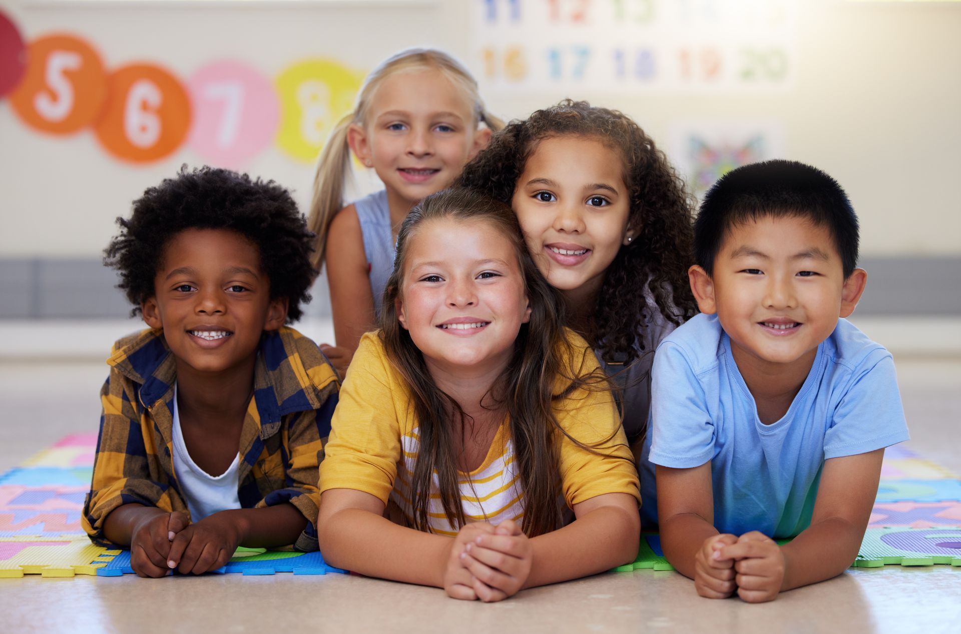 A group of children are posing for a picture while laying on the floor.