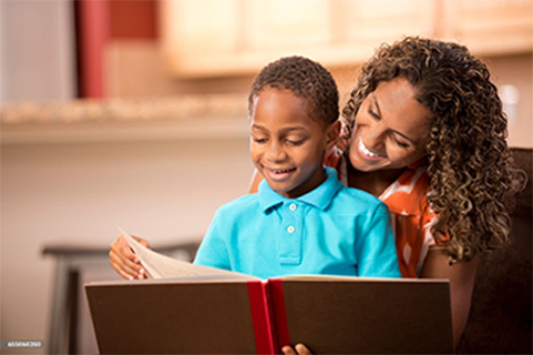 A woman is reading a book to a young boy.