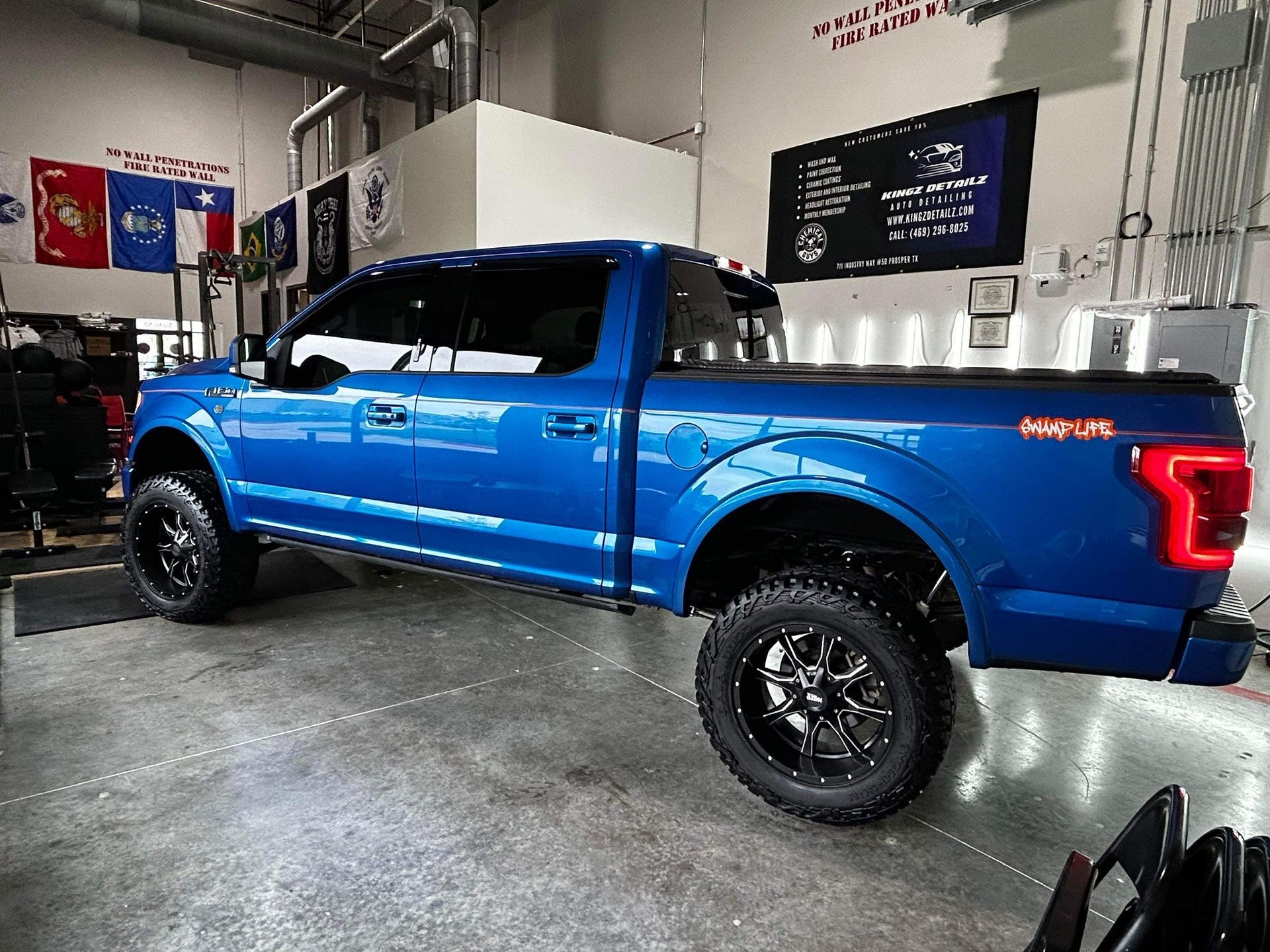 A blue pickup truck is parked in a garage.