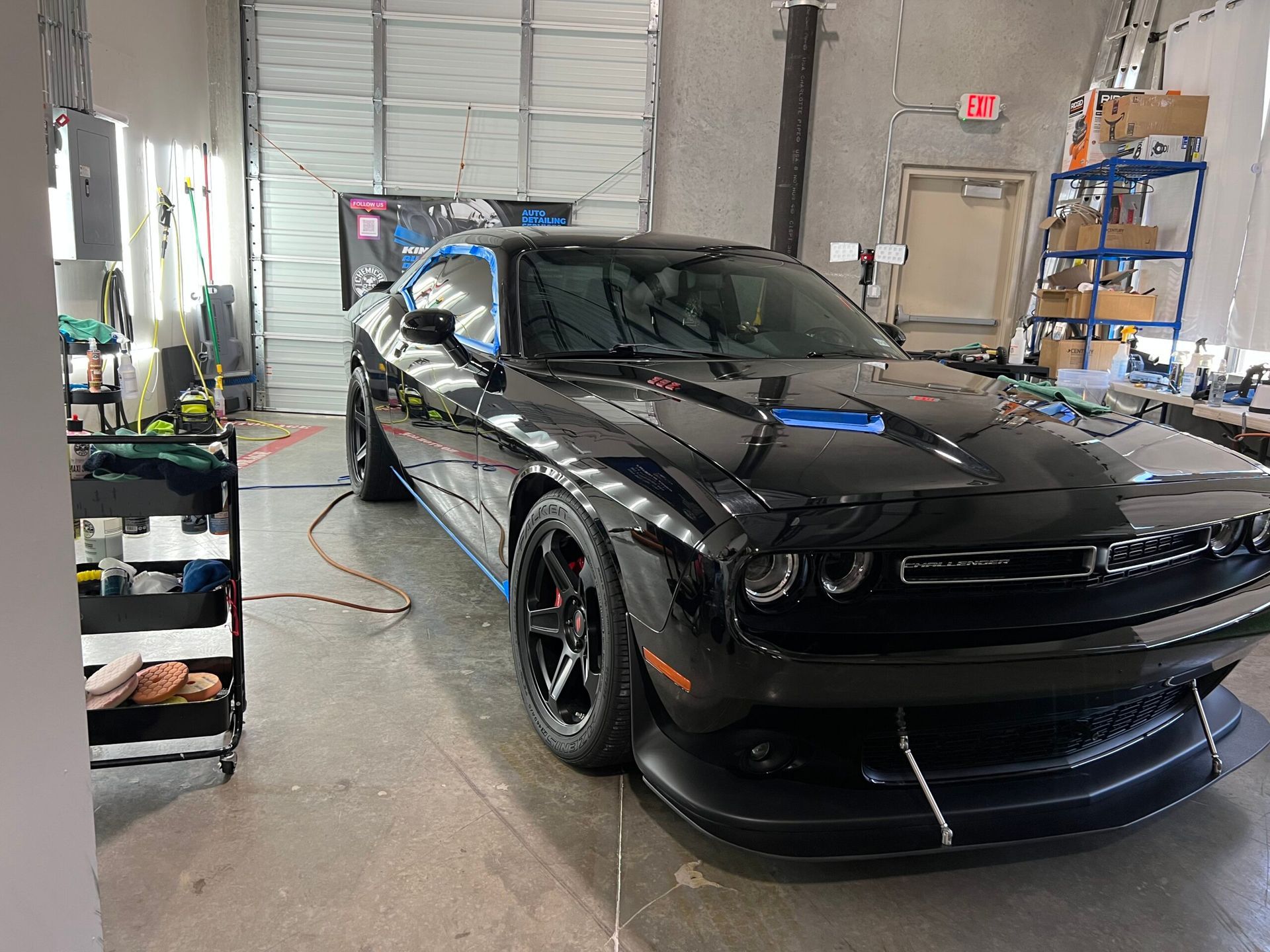 A black dodge challenger is parked in a garage.