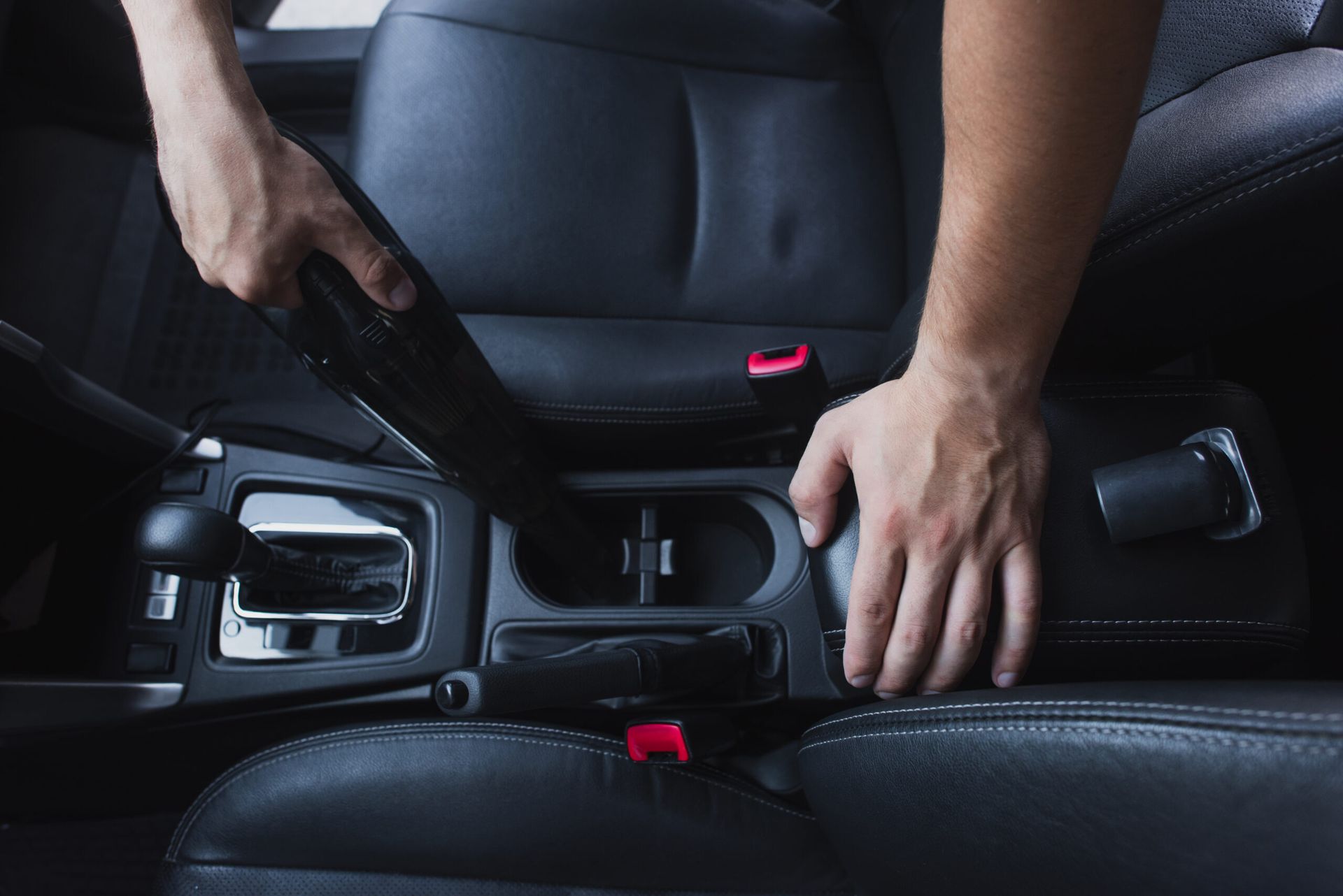 A person is cleaning the interior of a car with a vacuum cleaner.