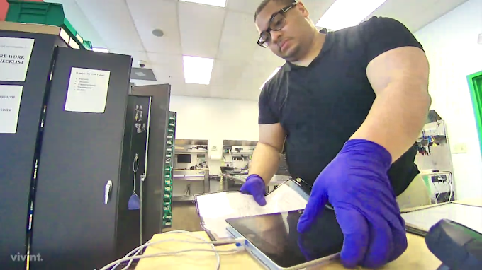 A man wearing purple gloves is working on a tablet computer.