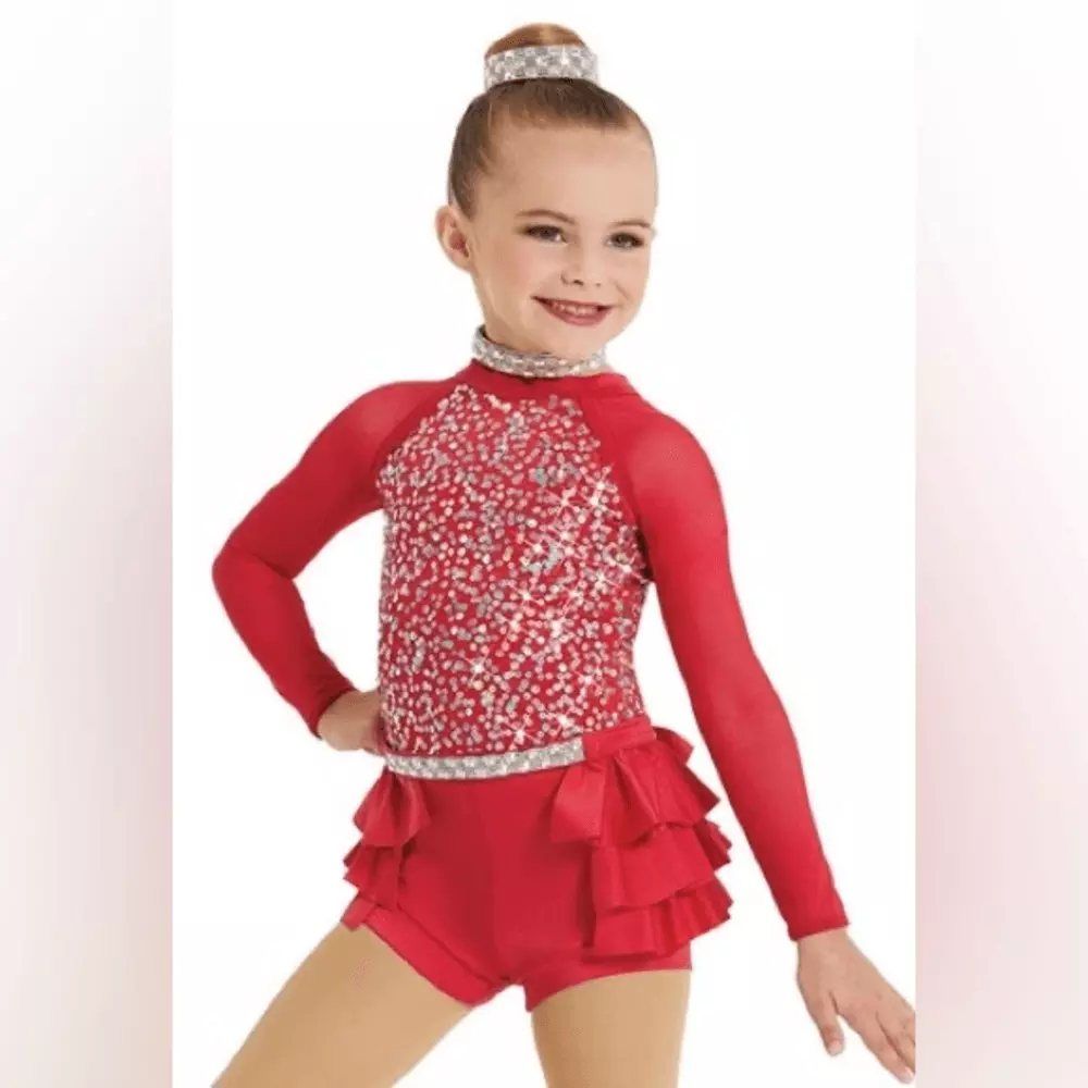 A little girl is wearing a red leotard with sequins and ruffles