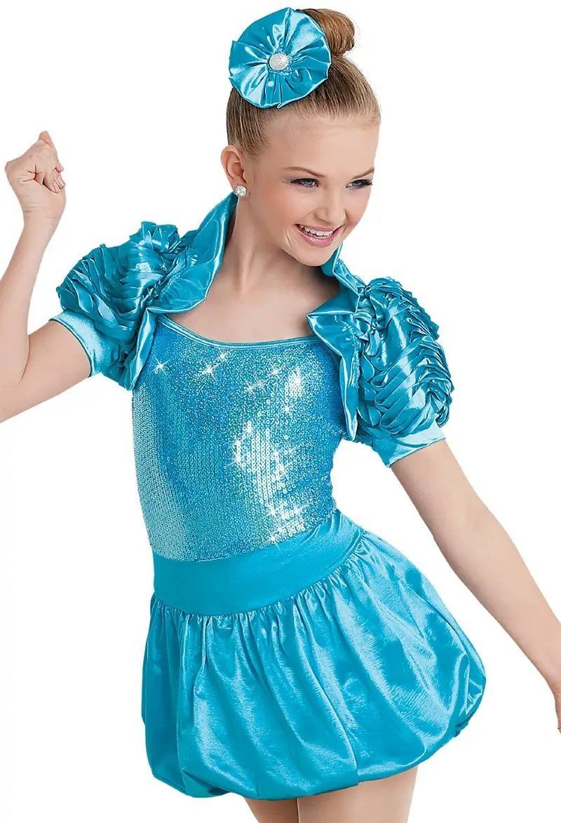 A young girl is wearing a blue sequined dress and a flower in her hair.