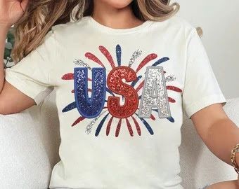 A woman is wearing a white t-shirt with the word usa on it.
