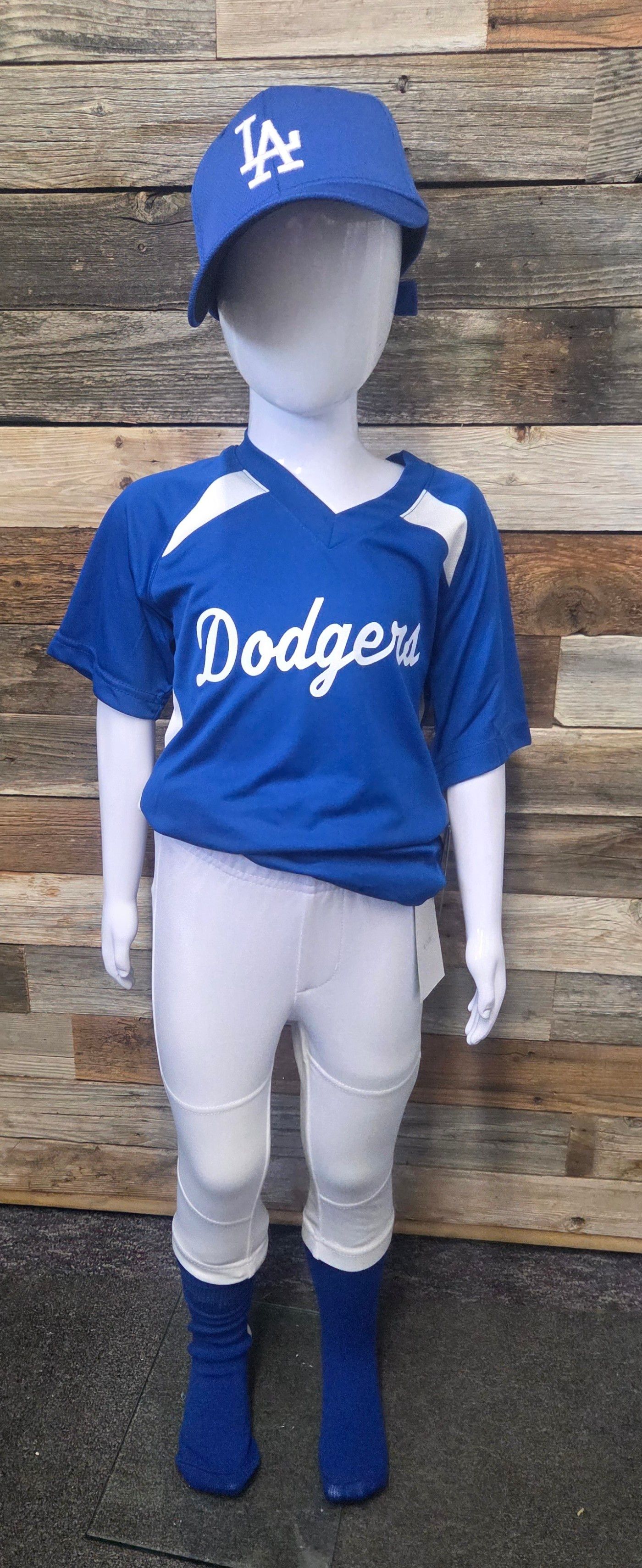 A child's Dodgers baseball uniform on a mannequin. Blue jersey, hat, and socks, white pants.
