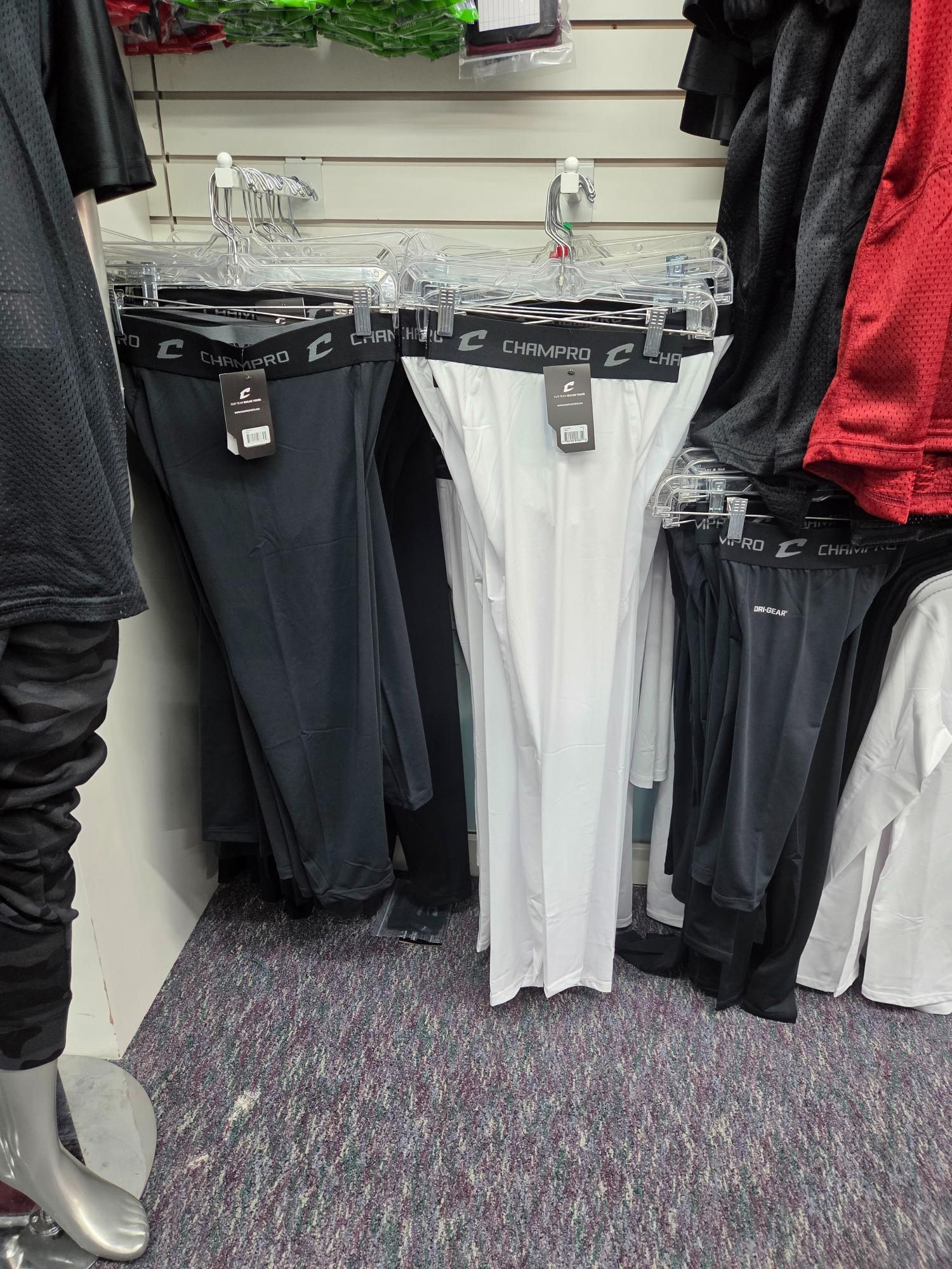 Athletic compression pants hanging on a store rack, various colors visible.