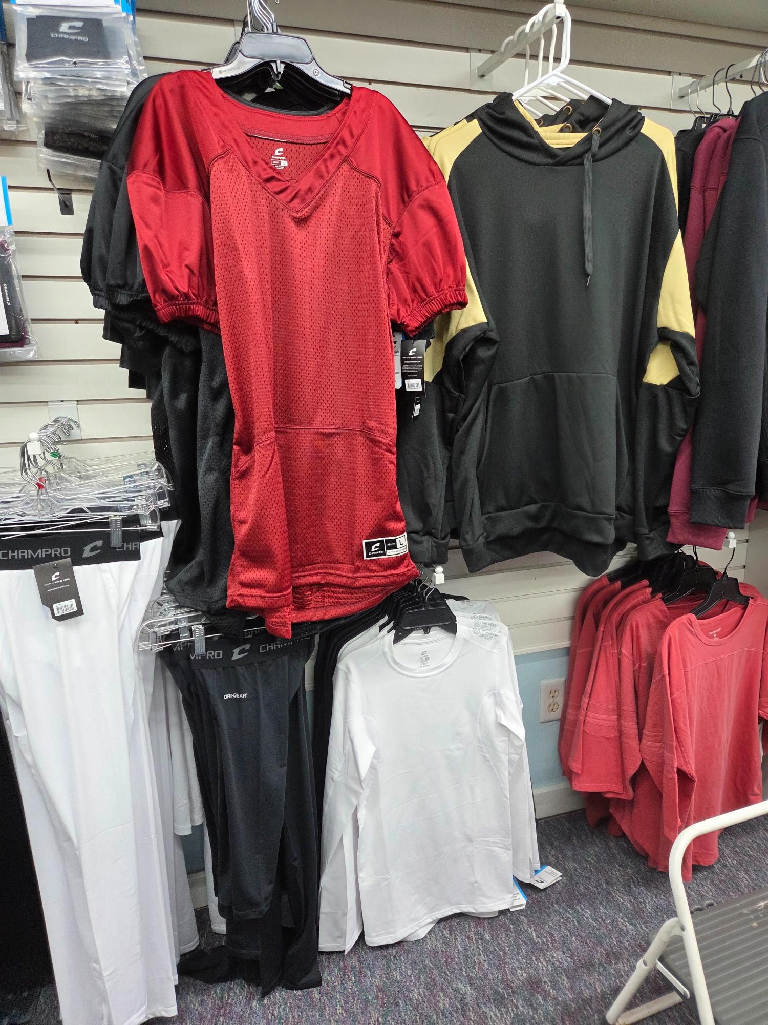 Clothing display: red jersey, black hoodie with gold sleeves, white long-sleeve shirts, and black pants.