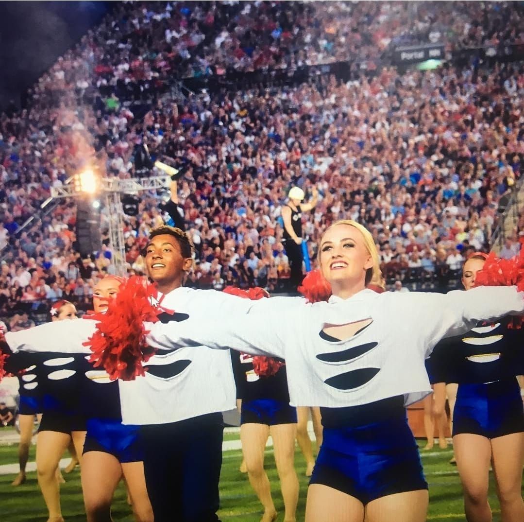 A group of cheerleaders are dancing in front of a crowd