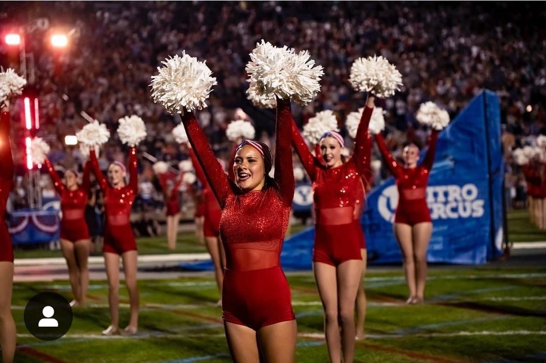 A group of cheerleaders are performing on a football field.