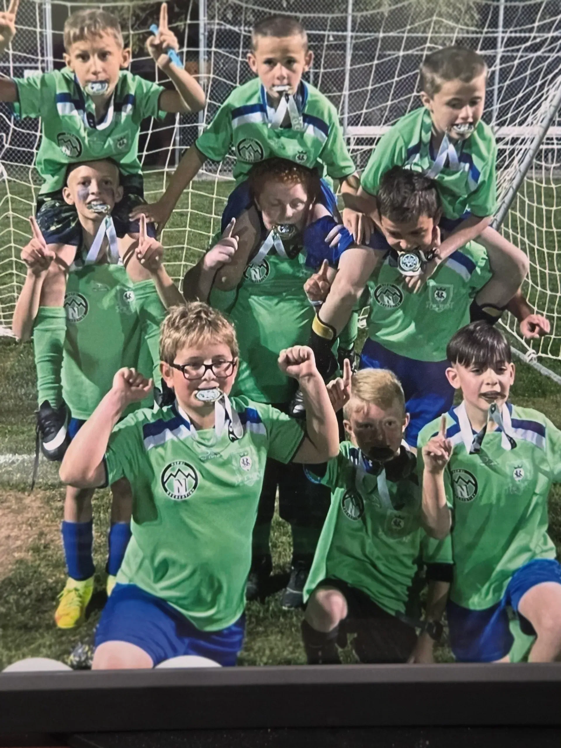 A group of young boys are posing for a picture on a soccer field.