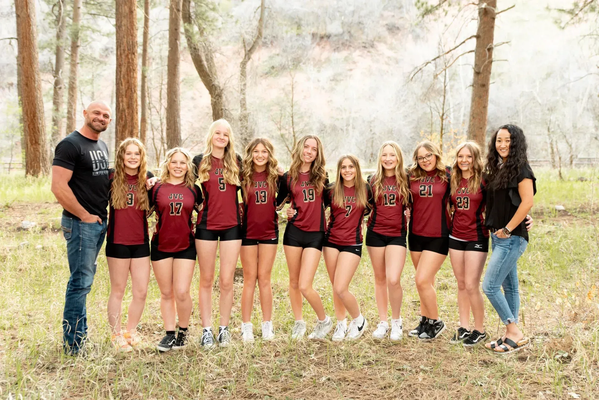 A group of young girls are posing for a picture in the woods.