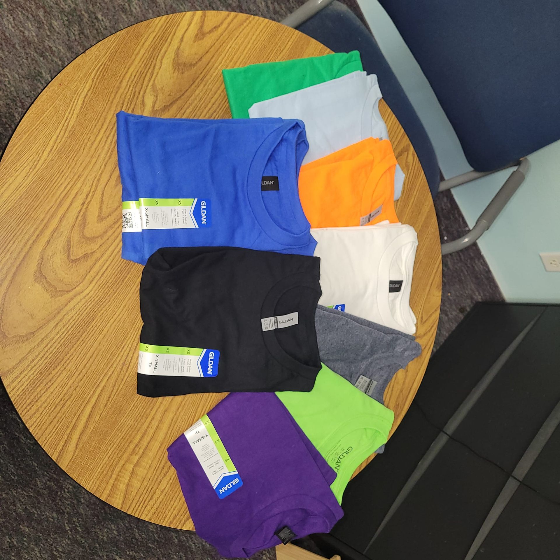 A bunch of t-shirts on a round wooden table