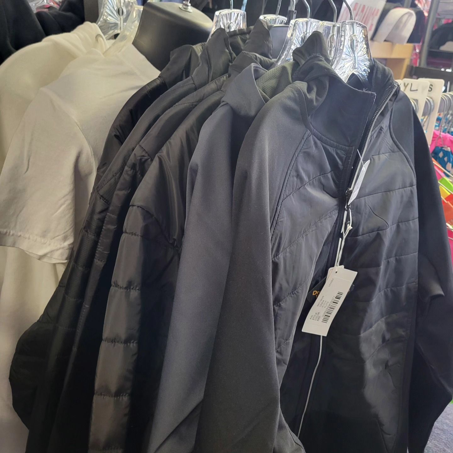 A bunch of jackets are hanging on a rack in a store