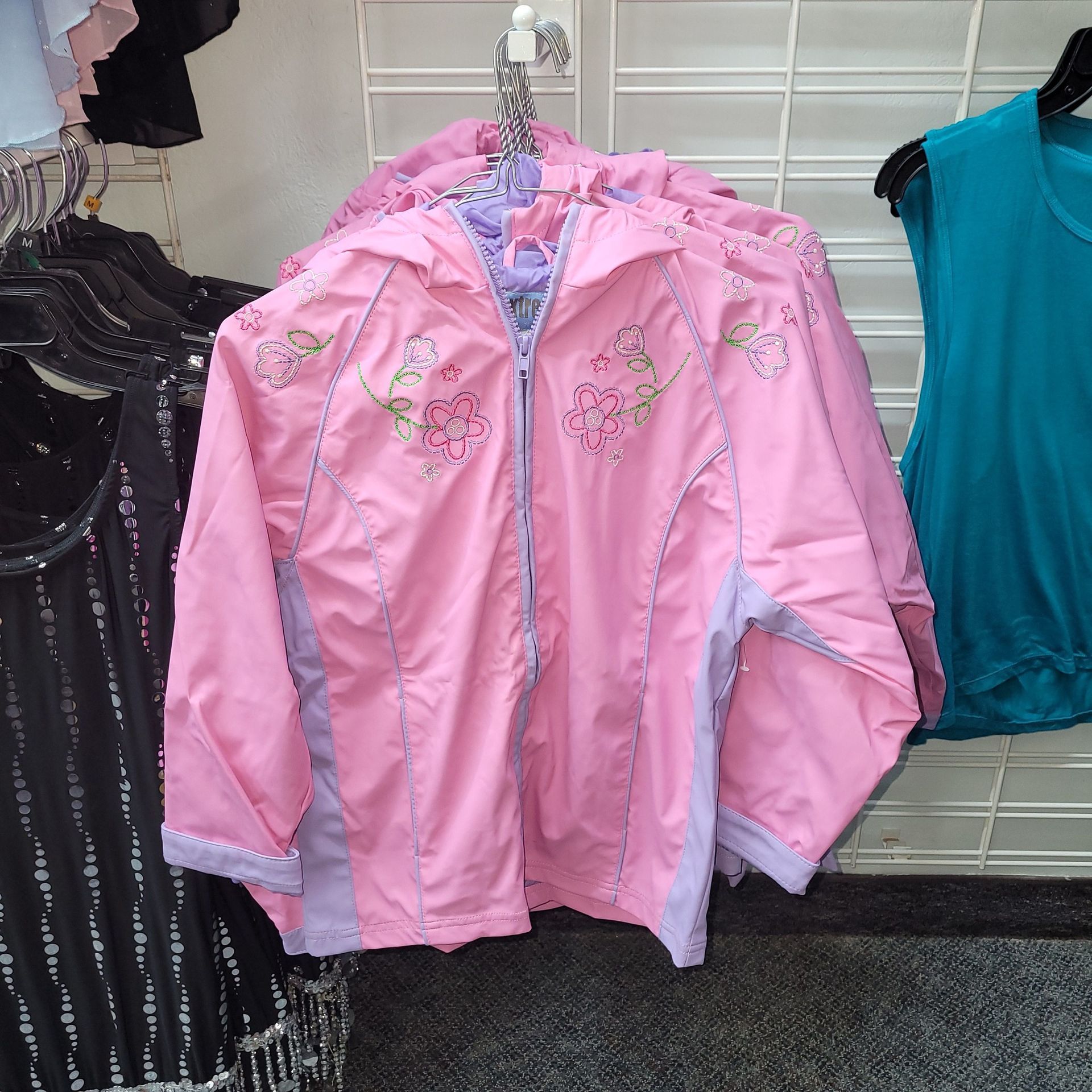 A pink jacket with flowers on it hangs in a store