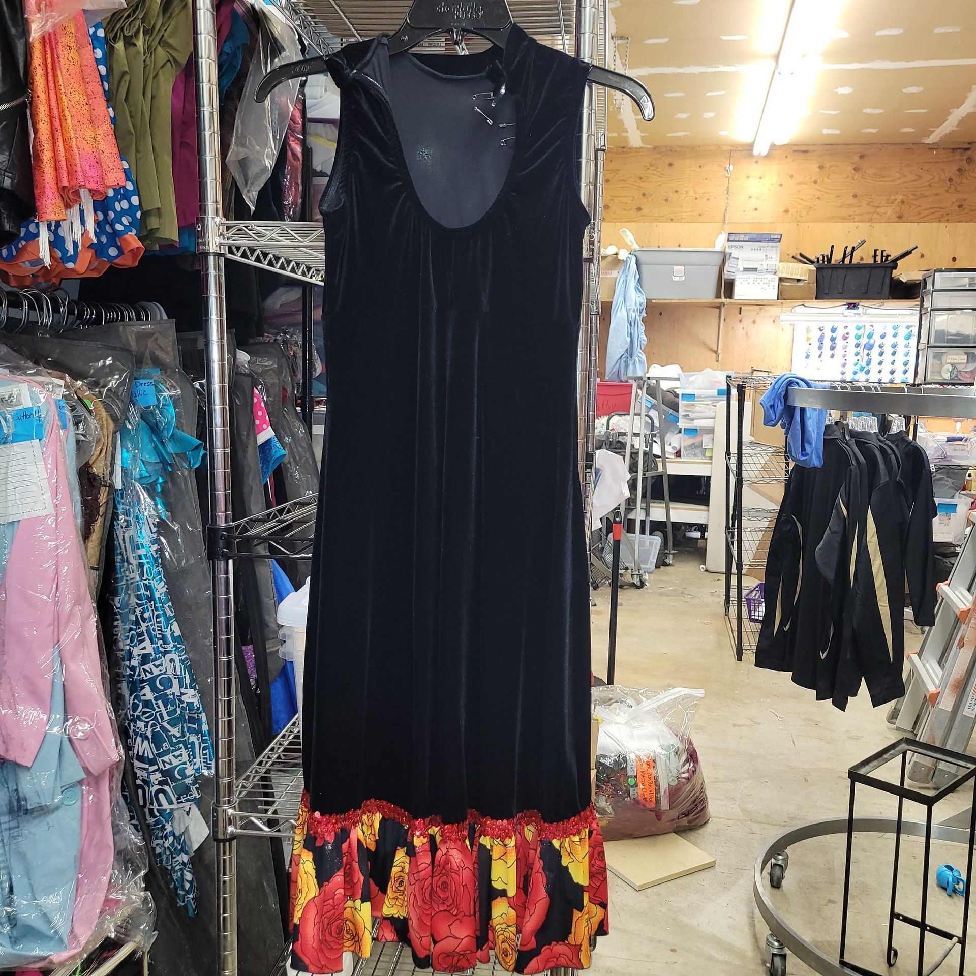 A black dress with flames on the bottom is hanging on a rack in a store